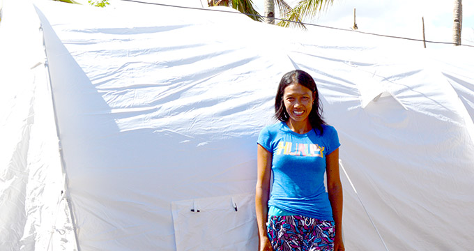 Rose Castro stands in front of the family tent which she received from Irish Aid after her home was destroyed by Typhoon Haiyan.
