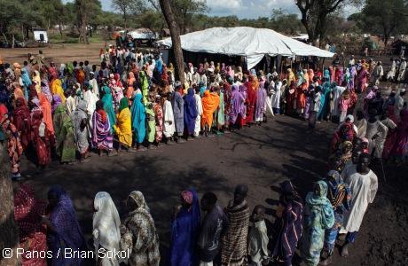 Sudanese refugees queue for blankets and mosquito nets at a distribution point in Yusuf Batil Refugee Camp. Photo: Panos / Brian Solol