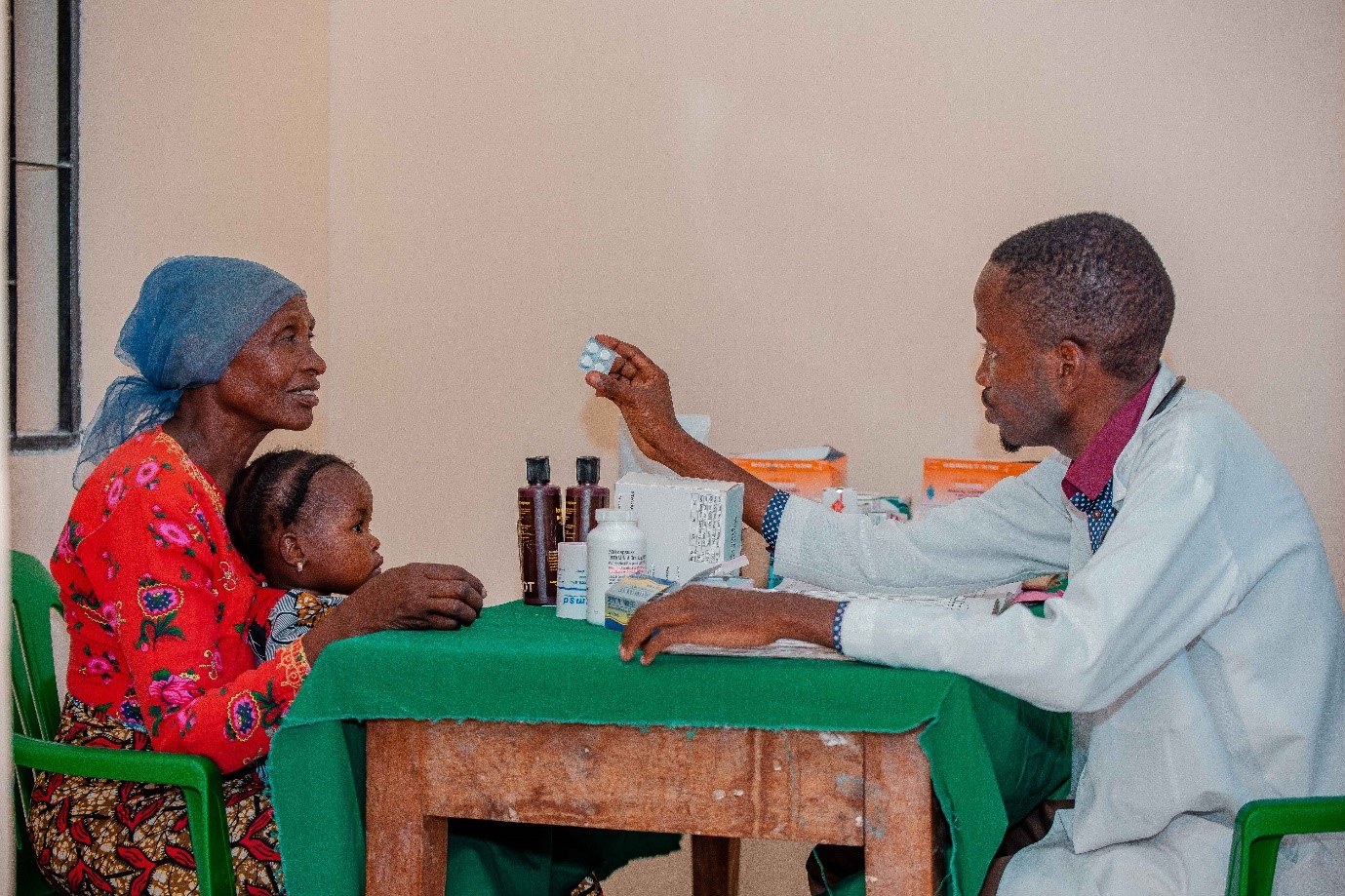 A doctor in Tanzania giving a woman and child some medicine.
